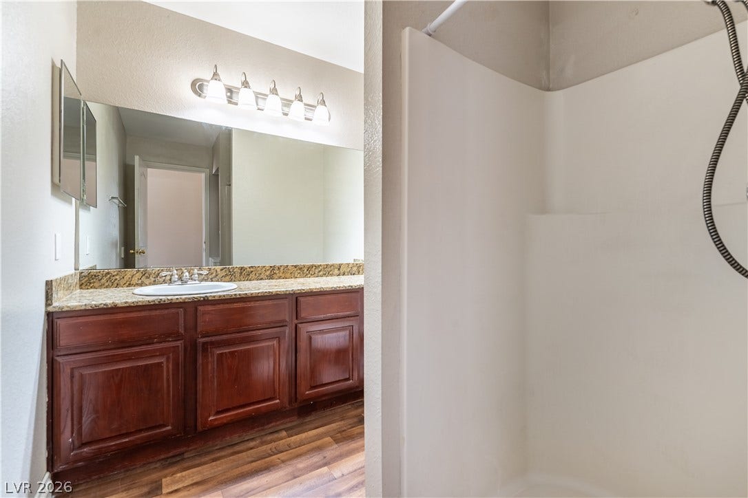 4050 Pacific Harbors Drive, #203, Las Vegas, NV 89121 Rich wood cabinetry and stone countertops anchor this classic bathroom space.