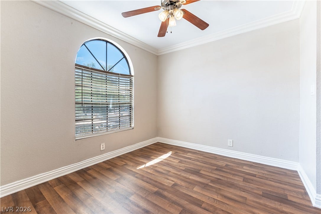 4050 Pacific Harbors Drive, #203, Las Vegas, NV 89121 Rich wood-inspired floors and crown molding complement an arched window in this versatile space.