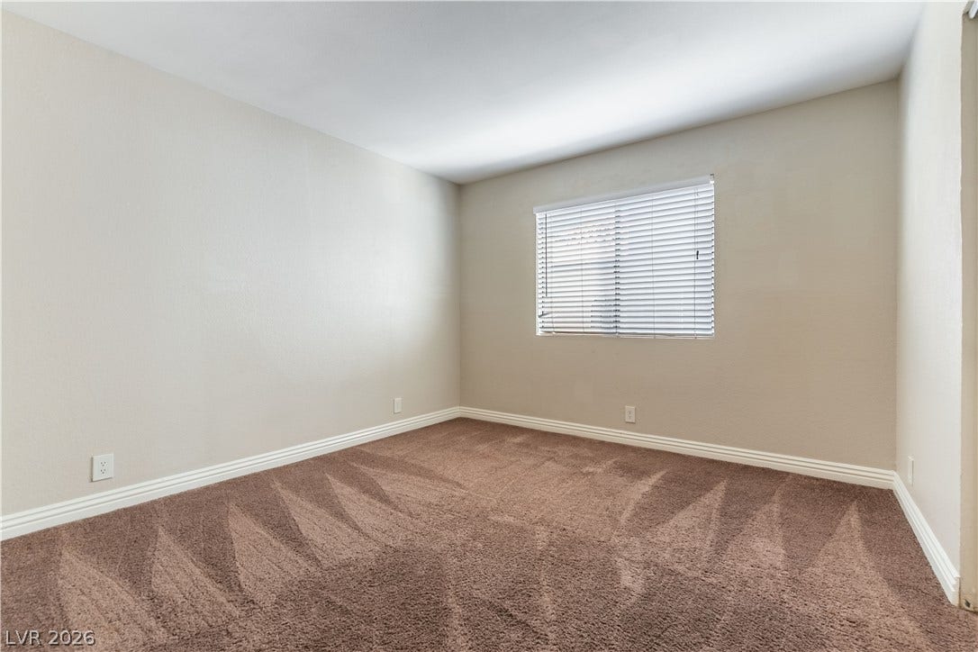 4050 Pacific Harbors Drive, #203, Las Vegas, NV 89121 Plush carpeted flooring and classic baseboards anchor this versatile bedroom space.