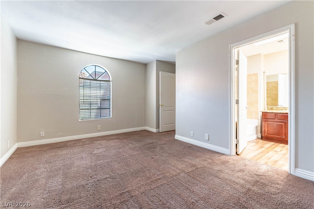 4050 Pacific Harbors Drive, #203, Las Vegas, NV 89121 Plush carpeting and an arched window define this comfortable bedroom space.
