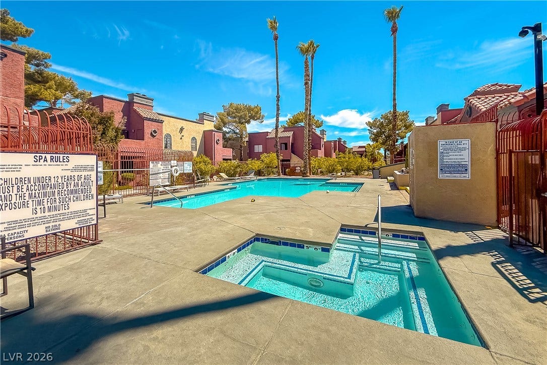 4050 Pacific Harbors Drive, #203, Las Vegas, NV 89121 Palm trees frame a sparkling community pool and spa area surrounded by tile-roofed residences.