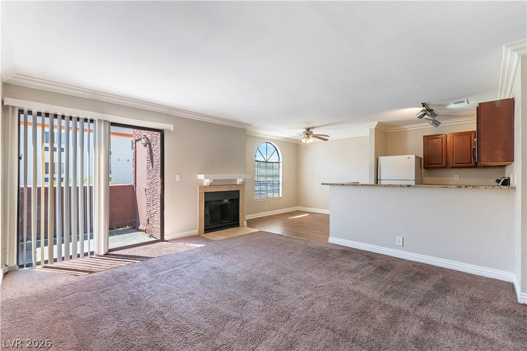 4050 Pacific Harbors Drive, #203, Las Vegas, NV 89121 An open floorplan connects the carpeted living area and fireplace to the nearby kitchen.