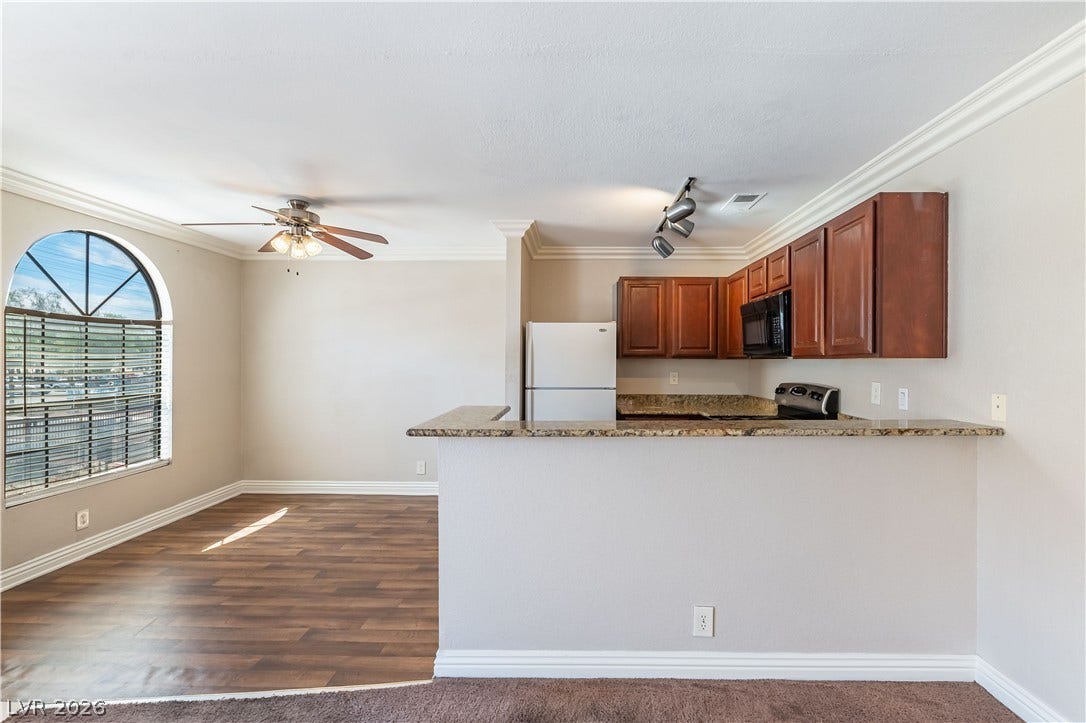 4050 Pacific Harbors Drive, #203, Las Vegas, NV 89121 Granite counters and rich wood cabinetry define this functional, open-concept kitchen space.