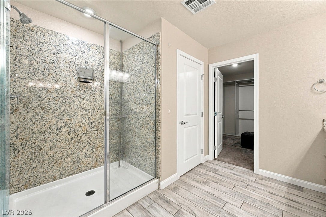 4216 Campriani Avenue, North Las Vegas, NV 89084 Plank tile flooring and a spacious walk-in shower with stone surround define this master bathroom.