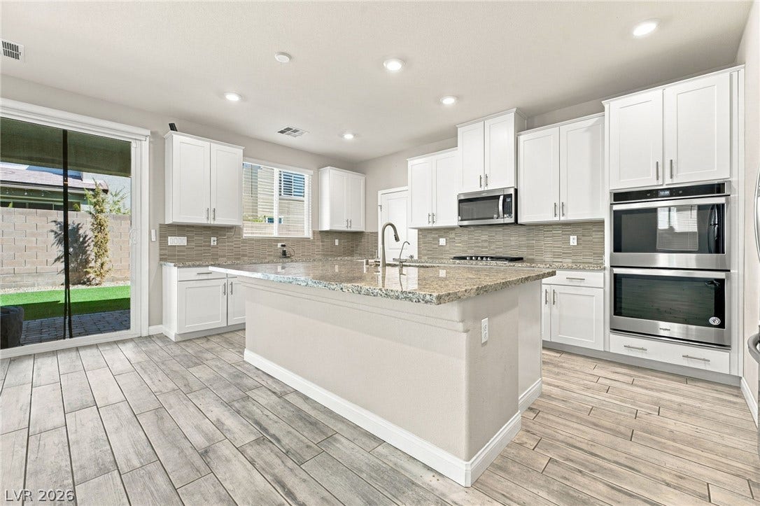 4216 Campriani Avenue, North Las Vegas, NV 89084 Granite countertops and white cabinetry anchor this modern kitchen anchored by a large central island.