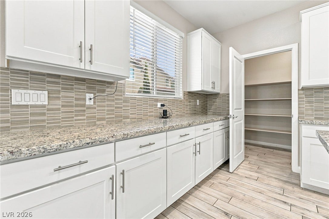 4216 Campriani Avenue, North Las Vegas, NV 89084 Granite countertops and clean cabinetry flank a large walk-in pantry with abundant shelving.