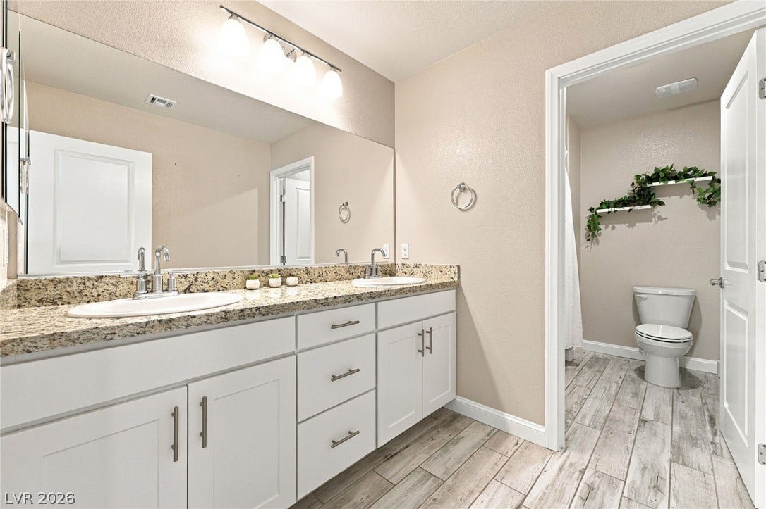 4216 Campriani Avenue, North Las Vegas, NV 89084 A spacious double vanity features granite countertops paired with light wood-look tile flooring.