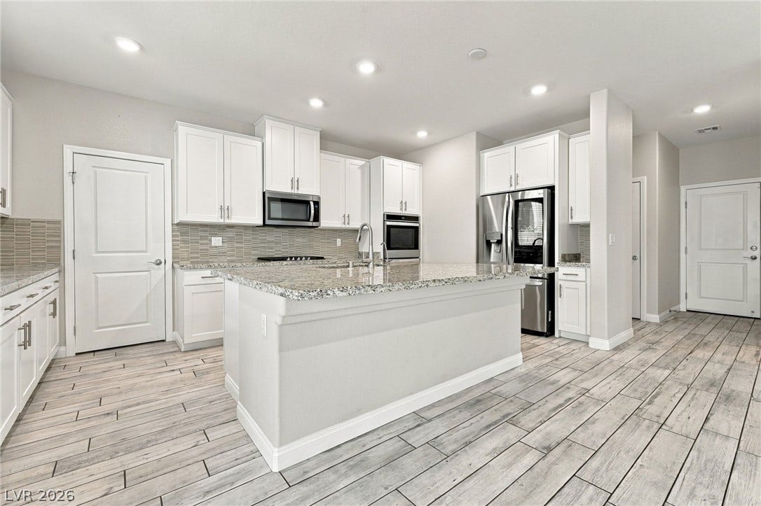 4216 Campriani Avenue, North Las Vegas, NV 89084 Polished granite countertops and classic white cabinetry define this stylish open kitchen space.
