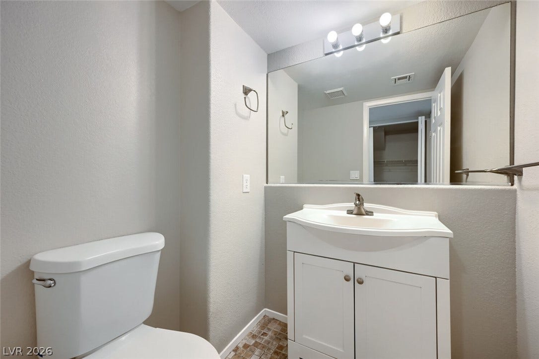 6027 Dawn View Lane, North Las Vegas, NV 89031 A clean powder room features a white vanity, large mirror, and tiled flooring.