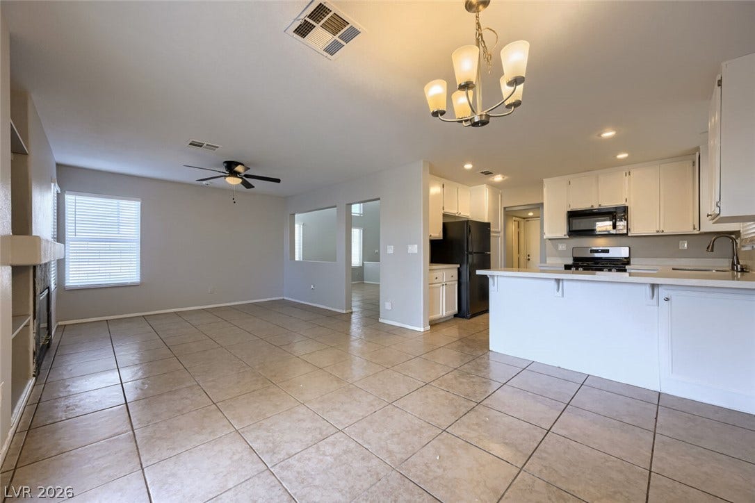 6027 Dawn View Lane, North Las Vegas, NV 89031 An open layout connects the kitchen to the tiled living area with fireplace.