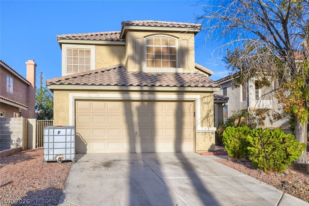 6027 Dawn View Lane, North Las Vegas, NV 89031 A classic stucco exterior features a tile roof and an attached double garage.
