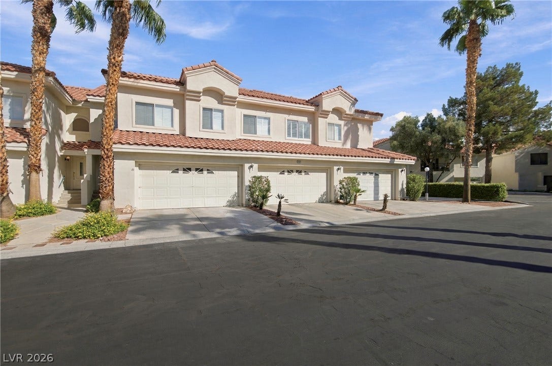 Palm trees frame the classic Mediterranean facade featuring a tiled roof and multi-car garages.
