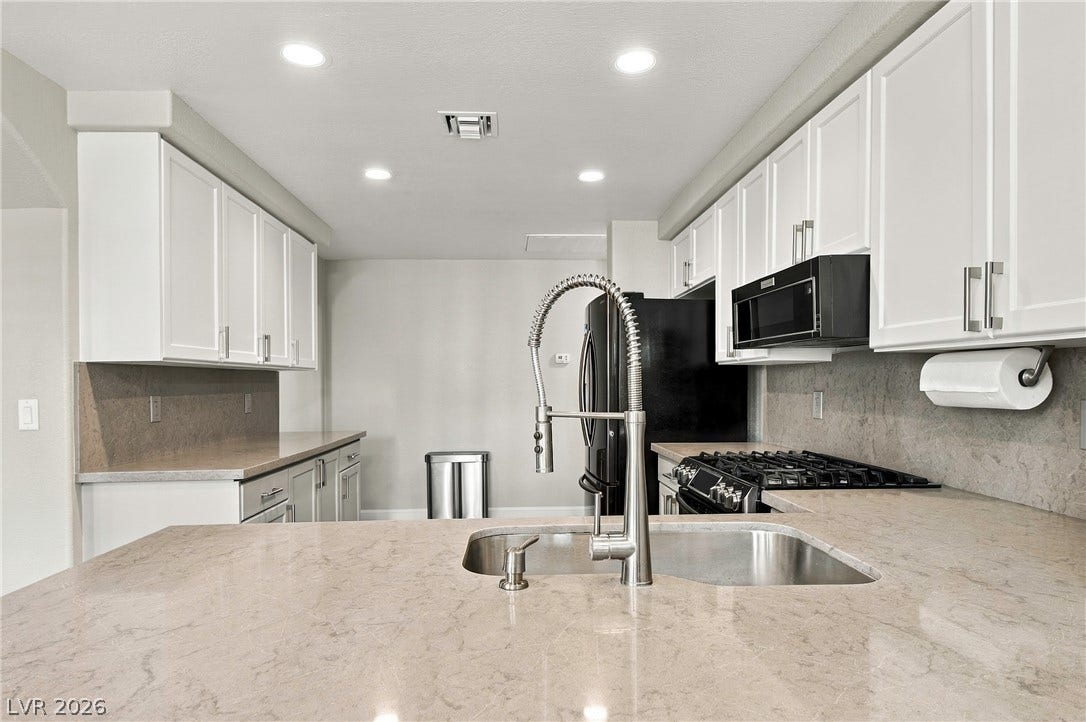 Smooth stone countertops pair beautifully with classic white cabinetry in this functional cooking space.