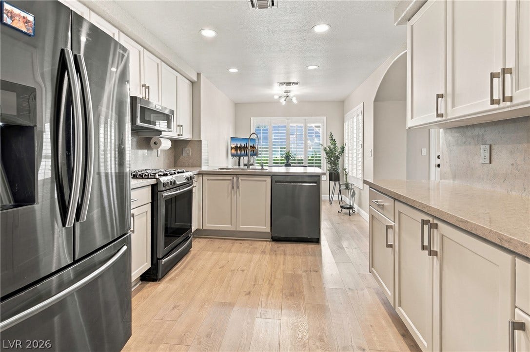 Warm wood-toned floors and stone countertops define this efficiently designed kitchen workspace.