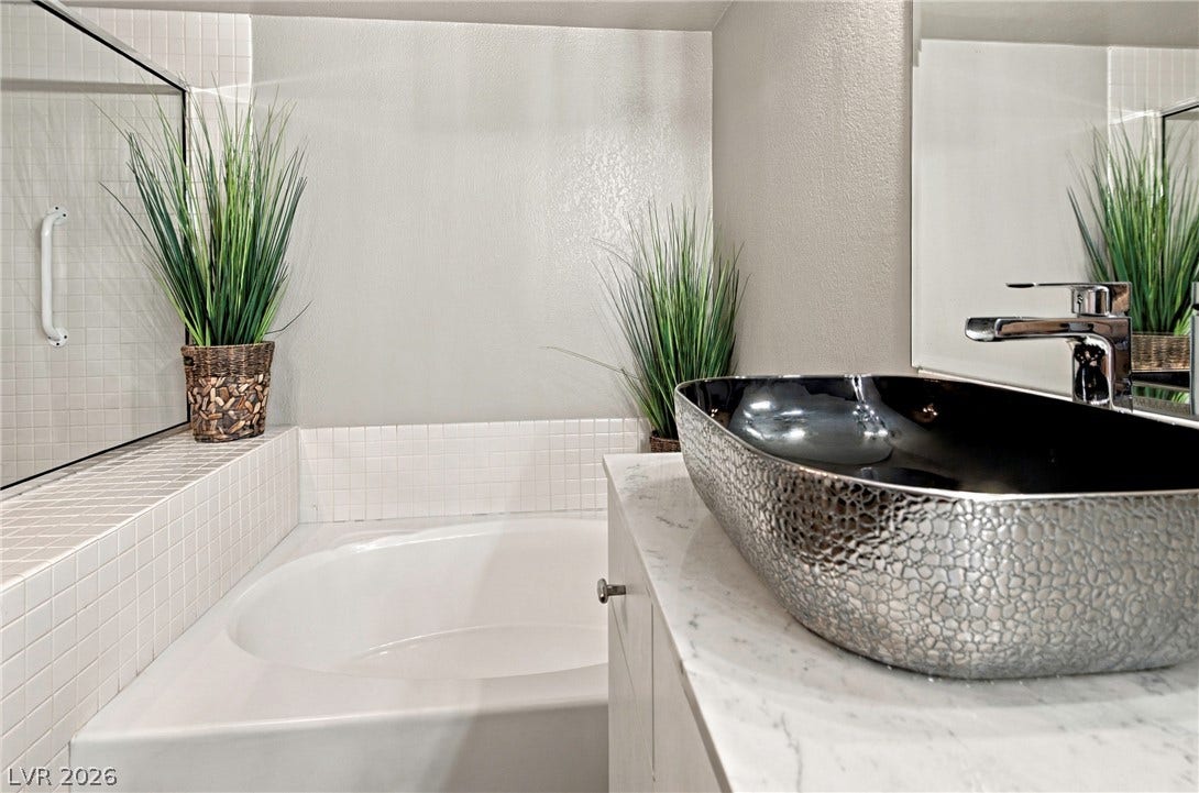 Polished stone counters and a deep soaking tub create a refined master bathroom oasis.