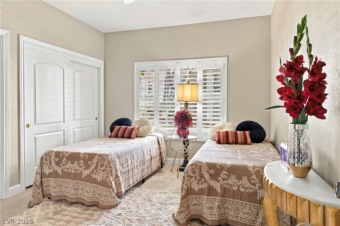 Plentiful natural light filters through plantation shutters into this comfortable bedroom with wood-style flooring.