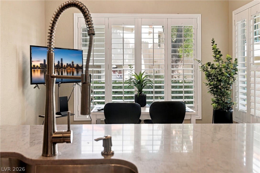 Gleaming stone countertops and classic plantation shutters enhance this bright culinary space.