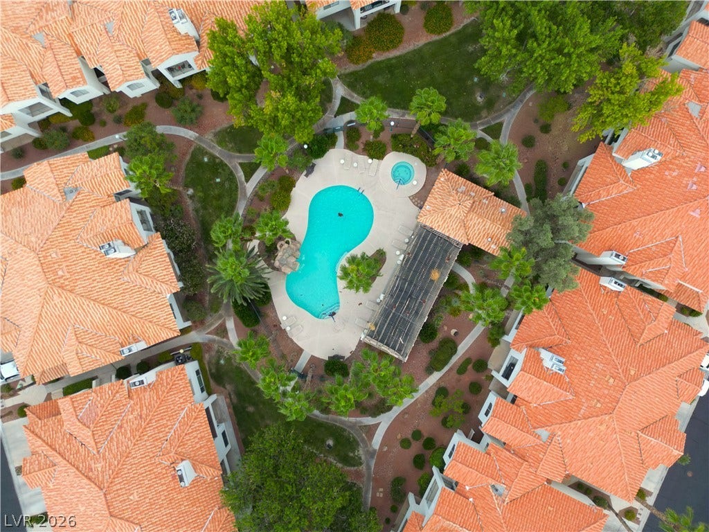 Lush landscaping and winding pathways surround a central swimming pool with spanish tile roofs.