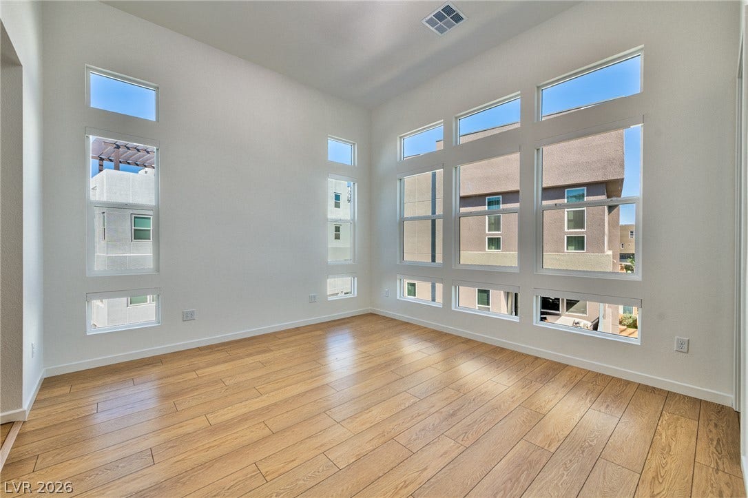 3327 Esker Ridge Avenue, Henderson, NV 89044 Sunlight streams through multiple tiers of windows onto rich hardwood flooring in this airy space.