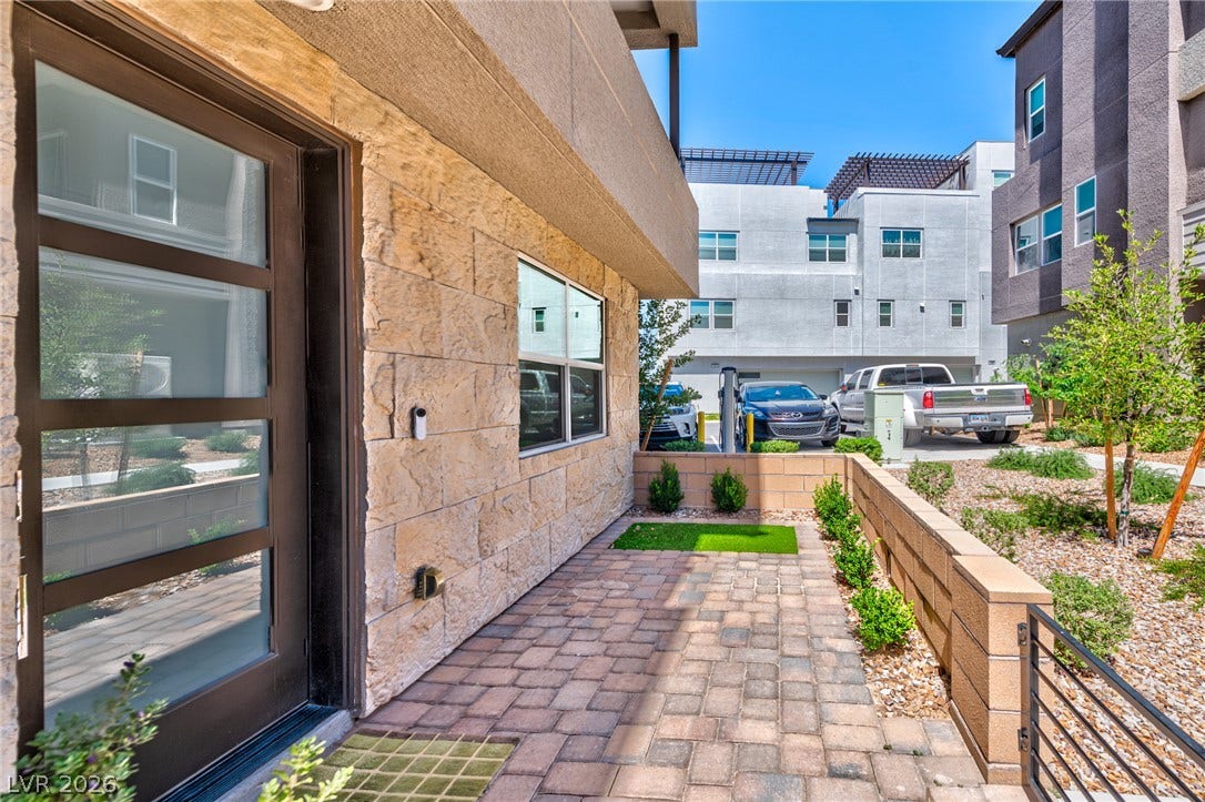 3327 Esker Ridge Avenue, Henderson, NV 89044 Textured stone siding and modern glass-paneled entryways elevate the contemporary exterior aesthetic.