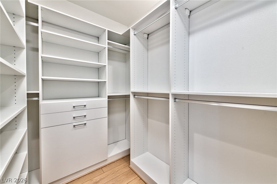 3327 Esker Ridge Avenue, Henderson, NV 89044 Custom built-in shelving and ample hanging rods maximize storage in this wood-floored walk-in closet.