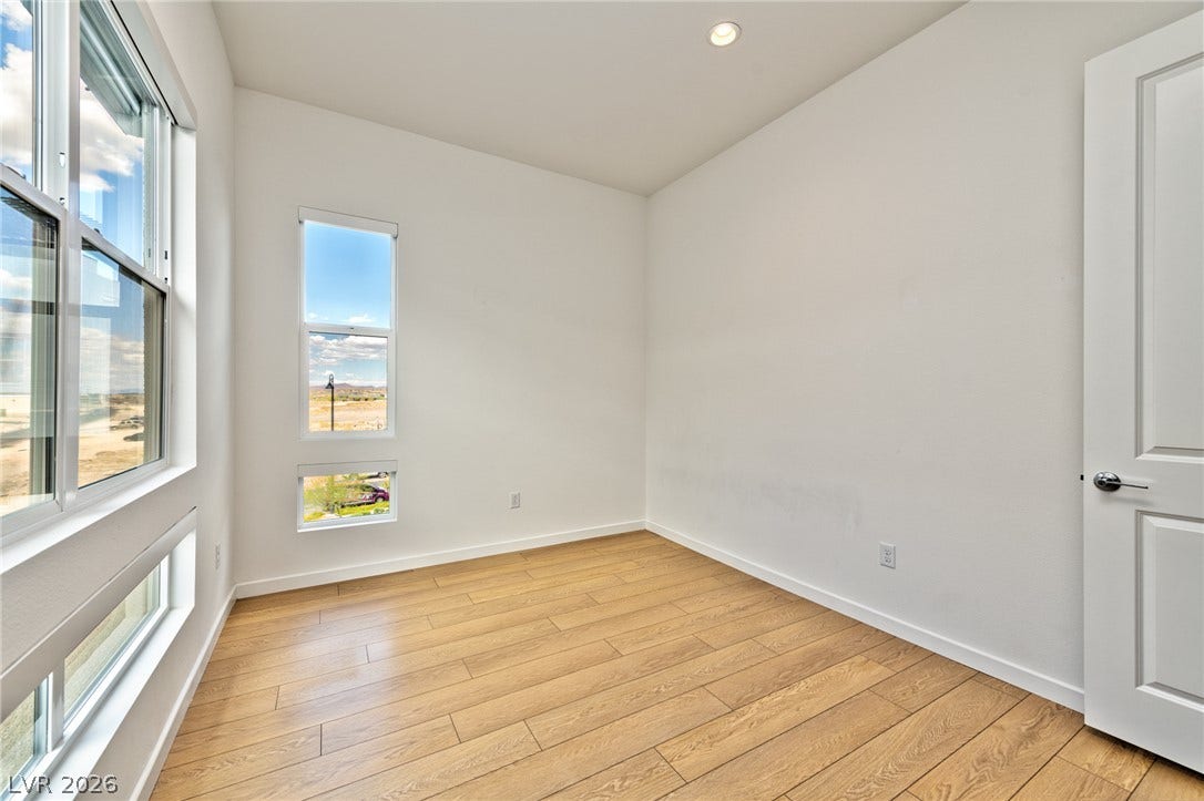 3327 Esker Ridge Avenue, Henderson, NV 89044 Warm wood flooring and clean white walls create a serene, minimalist bedroom retreat.