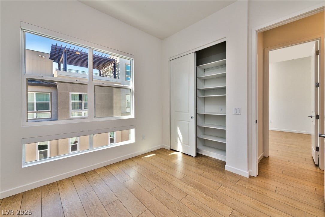 3327 Esker Ridge Avenue, Henderson, NV 89044 Natural light floods this modern bedroom featuring durable plank flooring and built-in closet shelving.