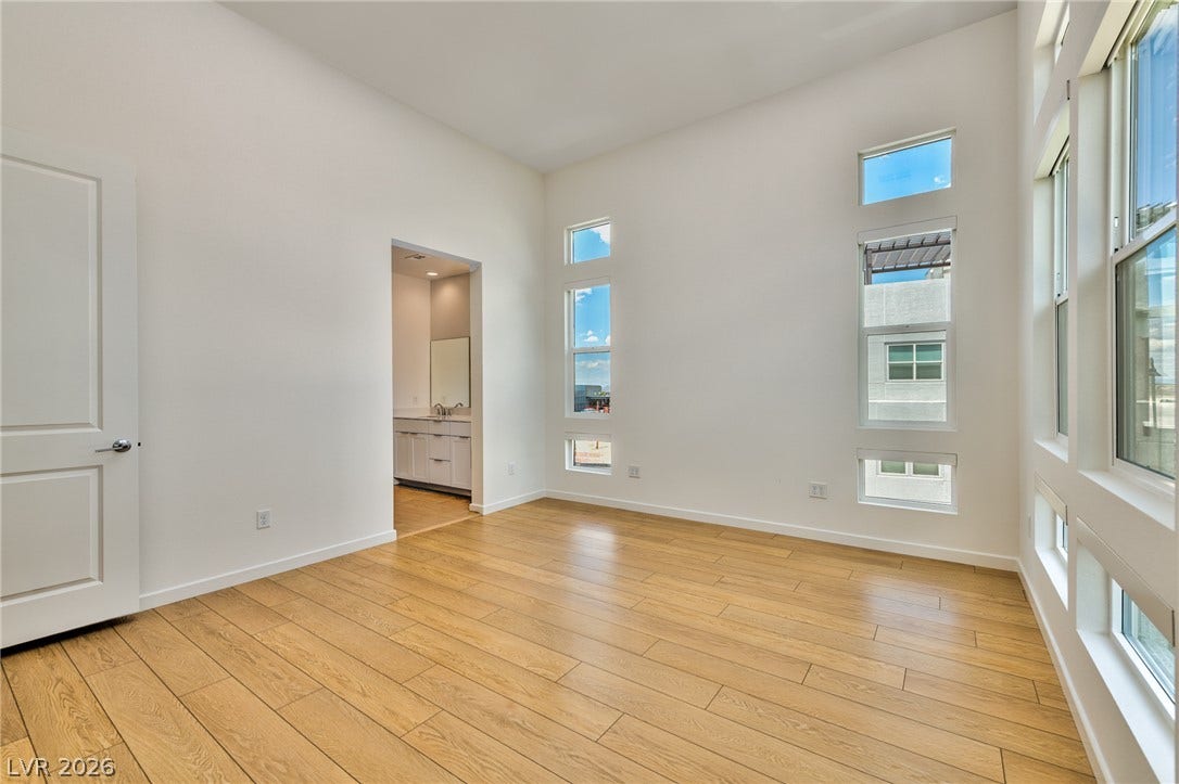 3327 Esker Ridge Avenue, Henderson, NV 89044 High ceilings and clean hardwood floors define this airy bedroom with custom window placements.