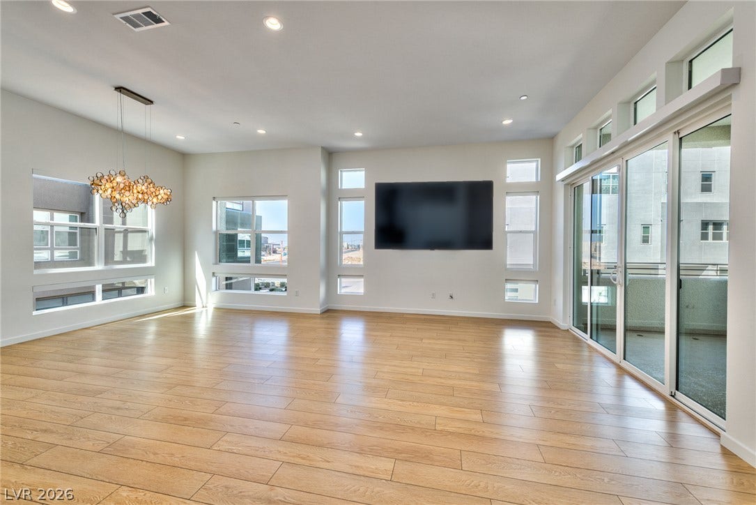 3327 Esker Ridge Avenue, Henderson, NV 89044 Polished wood-style flooring and abundant glass doors define this expansive open living space.