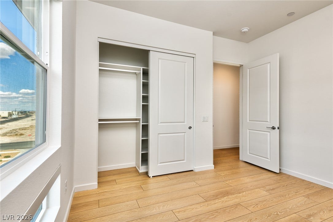 3327 Esker Ridge Avenue, Henderson, NV 89044 Gleaming wood-style flooring and built-in closet shelving define this bright bedroom.