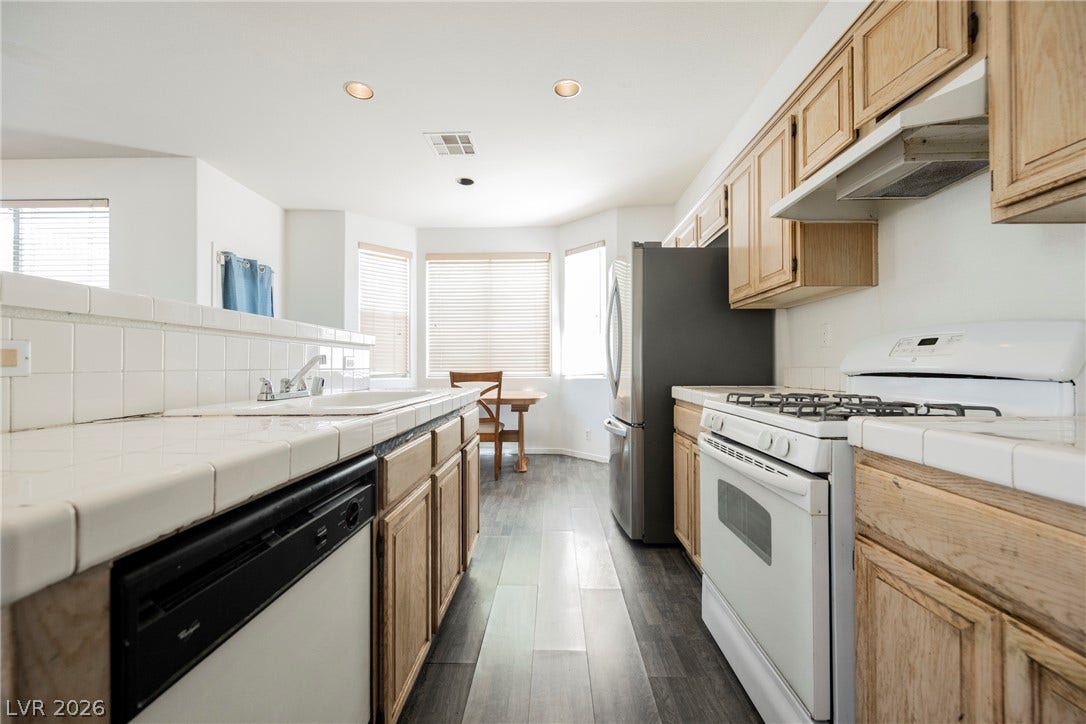 1608 Saddle Rock Circle, Las Vegas, NV 89117 Ample wooden cabinetry and durable tile countertops define this functional kitchen space.