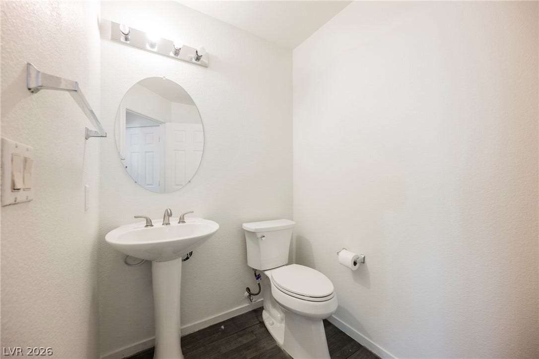 1608 Saddle Rock Circle, Las Vegas, NV 89117 A classic pedestal sink paired with dark wood-style flooring defines this clean powder room.