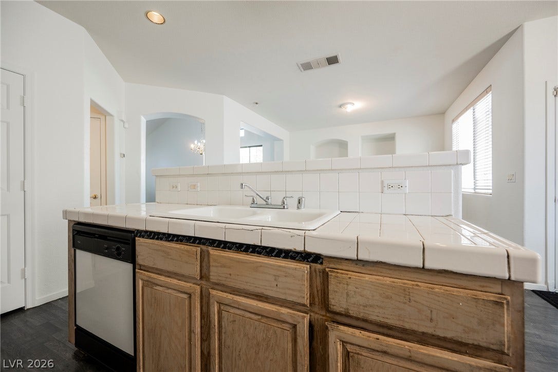 1608 Saddle Rock Circle, Las Vegas, NV 89117 Tiled countertops and a dual sink anchor this open kitchen space with wood cabinetry.