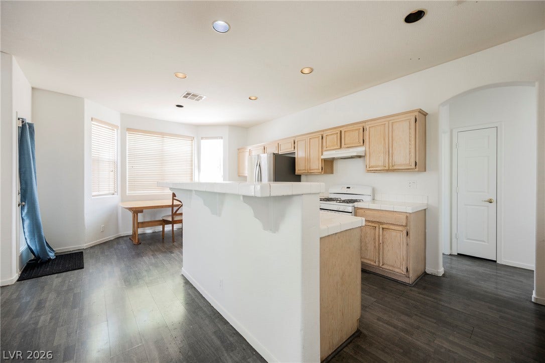 1608 Saddle Rock Circle, Las Vegas, NV 89117 Dark wood flooring contrasts with light cabinetry and countertops in this open kitchen layout.