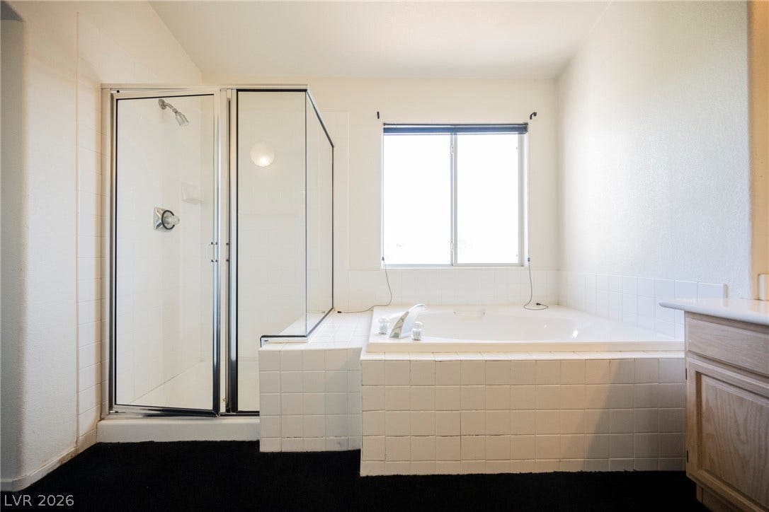 1608 Saddle Rock Circle, Las Vegas, NV 89117 Tiled finishes and natural light elevate this spacious primary bathroom featuring a separate tub and shower.