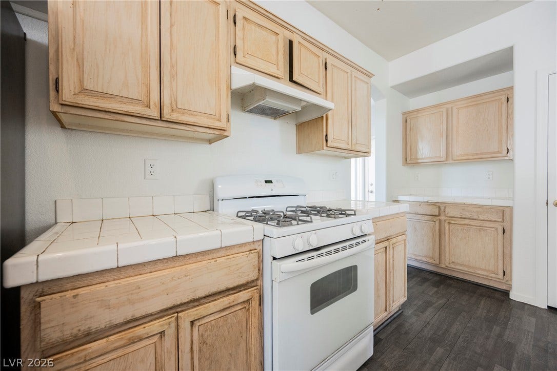 1608 Saddle Rock Circle, Las Vegas, NV 89117 Natural wood cabinetry pairs with tiled countertops and dark flooring in this functional kitchen.