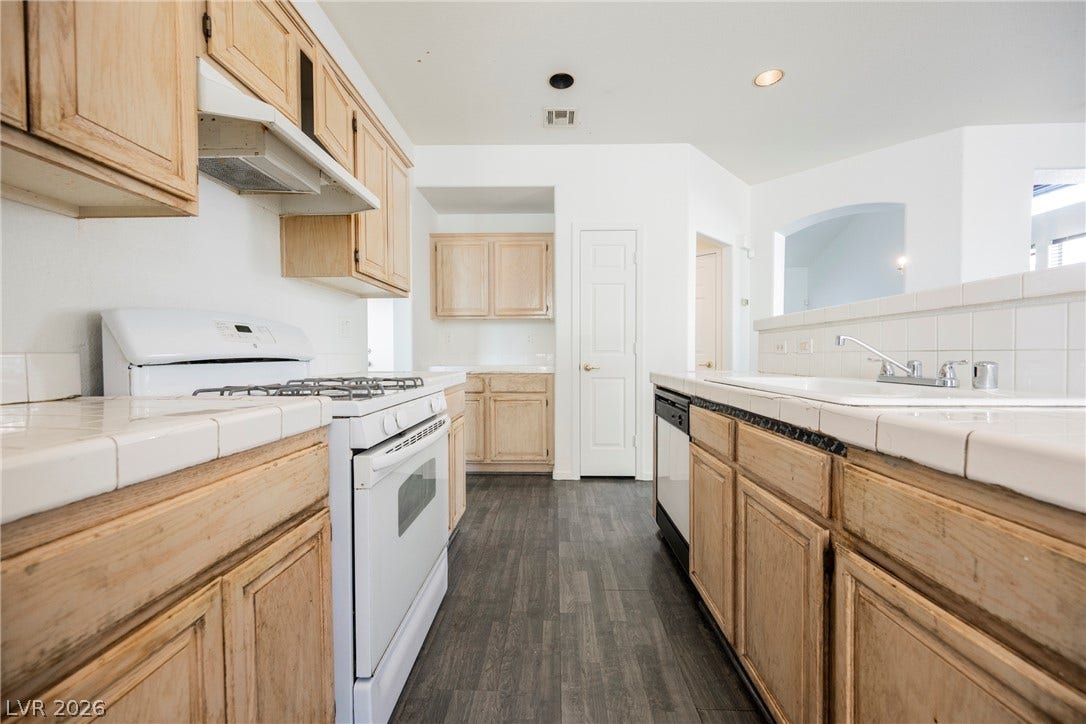 1608 Saddle Rock Circle, Las Vegas, NV 89117 Classic oak cabinetry and tiled countertops define this practical kitchen workspace.