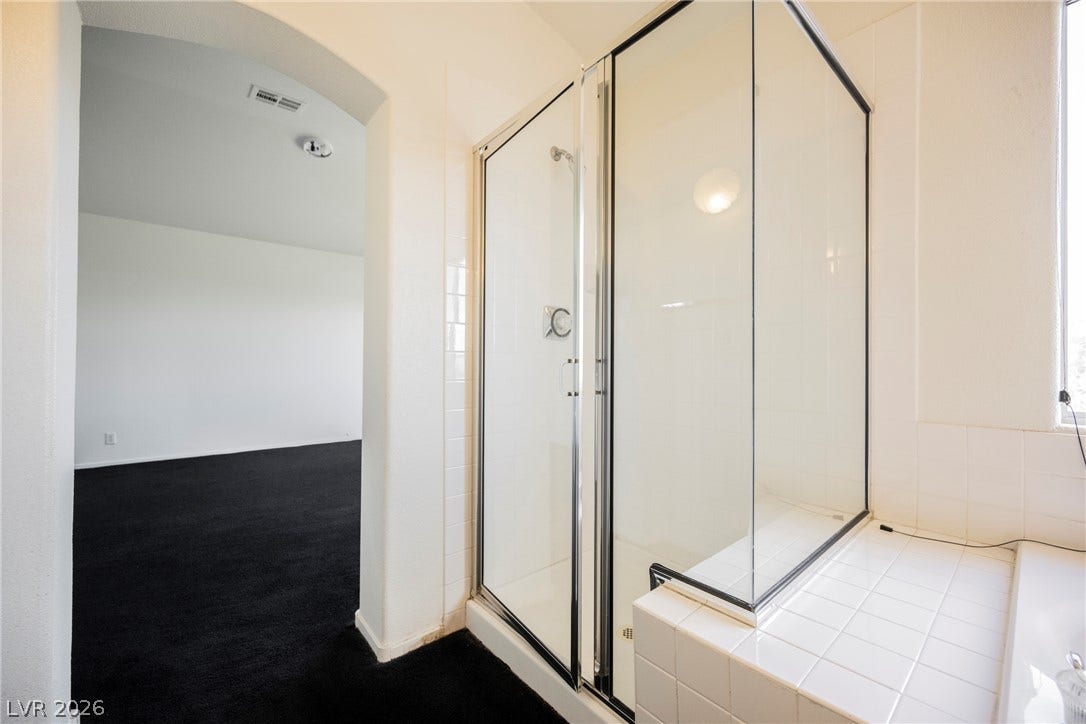 1608 Saddle Rock Circle, Las Vegas, NV 89117 A glass-enclosed shower stall stands adjacent to an arched doorway leading to carpeted living space.
