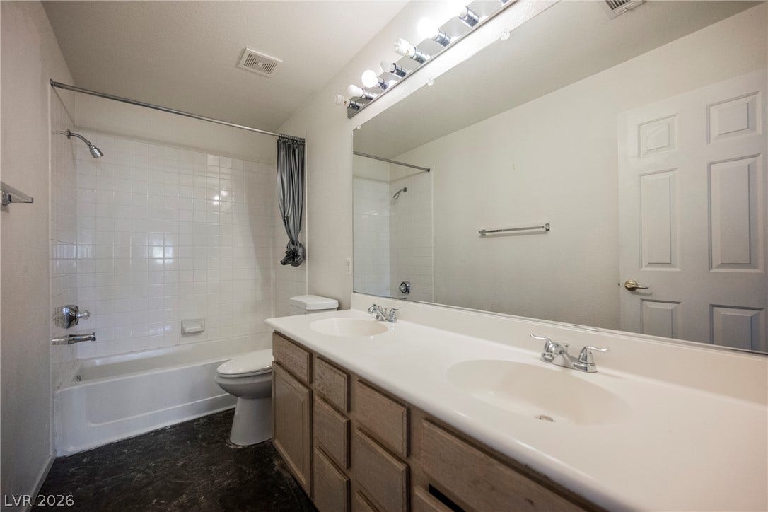 1608 Saddle Rock Circle, Las Vegas, NV 89117 Double vanities and a tiled shower-tub combination anchors this functional bathroom layout.