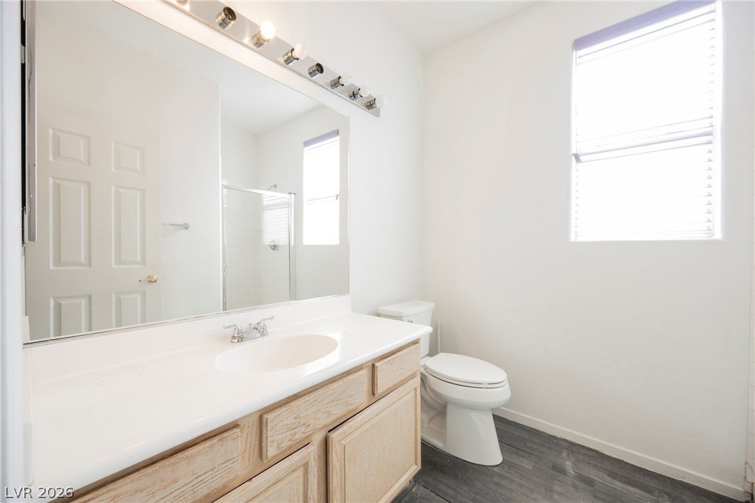 1608 Saddle Rock Circle, Las Vegas, NV 89117 Natural light illuminates a clean bathroom featuring a wood vanity and durable dark plank flooring.