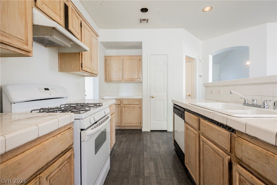 1608 Saddle Rock Circle, Las Vegas, NV 89117 Ample wooden cabinetry and classic tile countertops define this functional kitchen space.