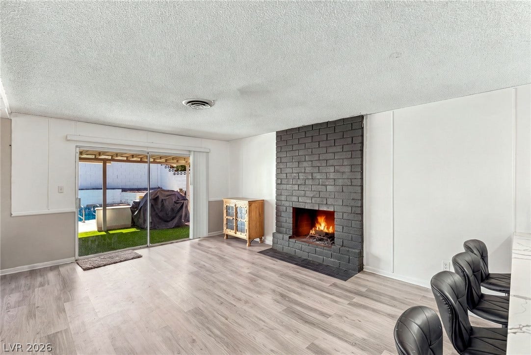 An inviting wood-burning brick fireplace anchors this open living space with sliding glass doors.
