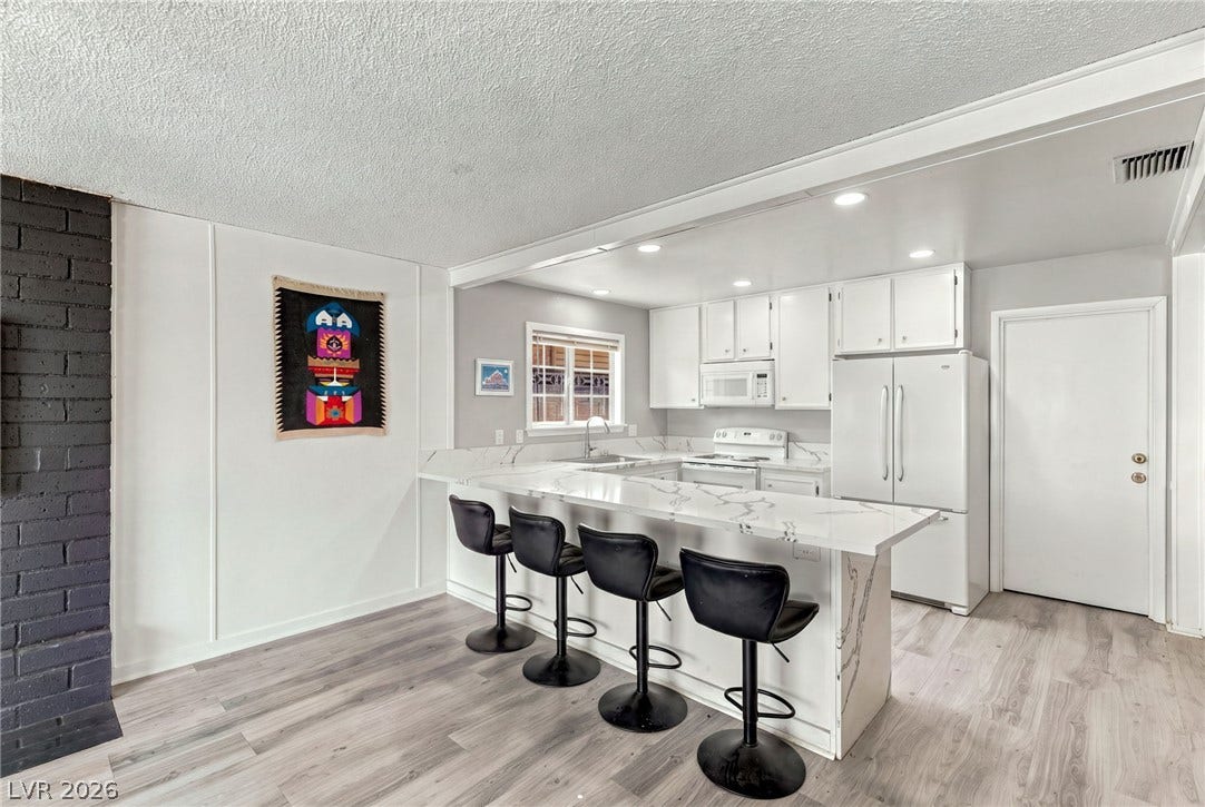 Streamlined kitchen workspace connects seamlessly to the dining area over a long quartz peninsula.