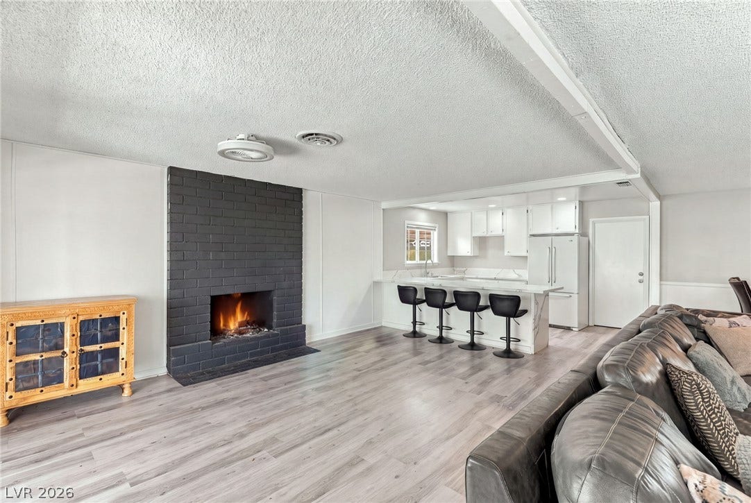 An open layout connects the living space and its fireplace to the modern kitchen.