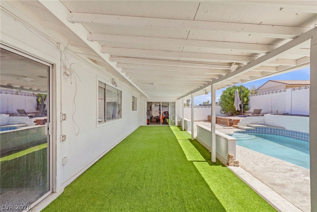 A covered patio with a beamed ceiling overlooks the backyard pool area.