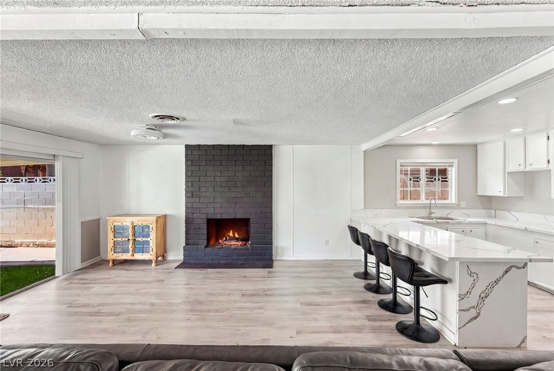 An open floorplan seamlessly connects the fireside living room with the adjacent modern kitchen.