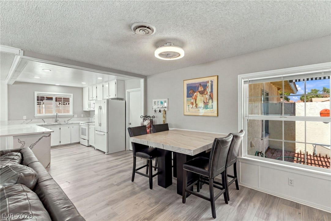 An open dining area flows into the kitchen over smooth plank flooring.