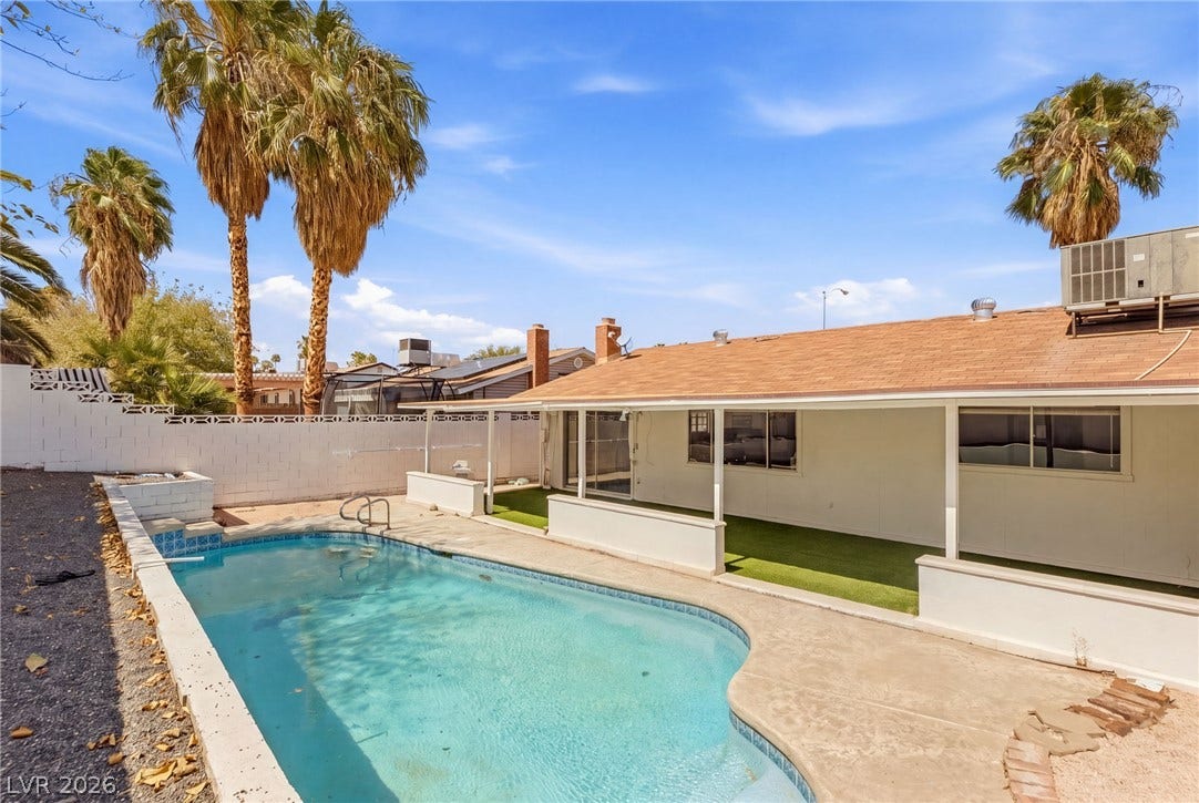 A refreshing in-ground pool anchors this sunny backyard complete with a covered patio area.