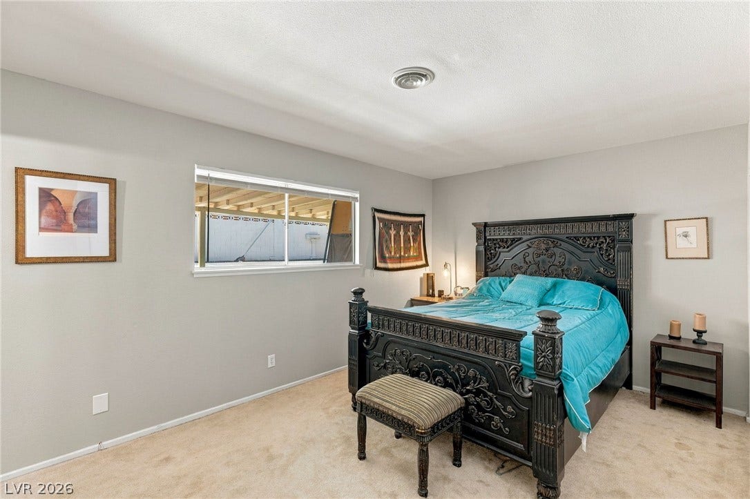 Plush carpeting and wide windows define this comfortable bedroom space.