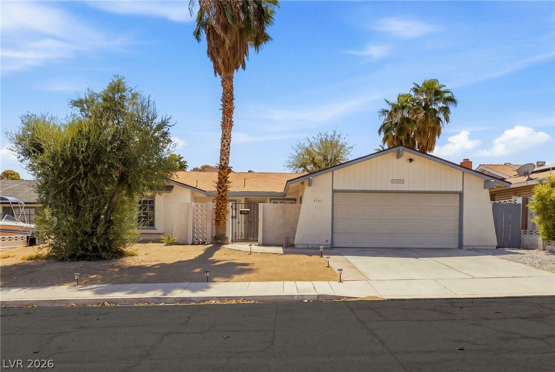 A classic single-story exterior features a wide driveway, attached garage, and desert-inspired landscaping.